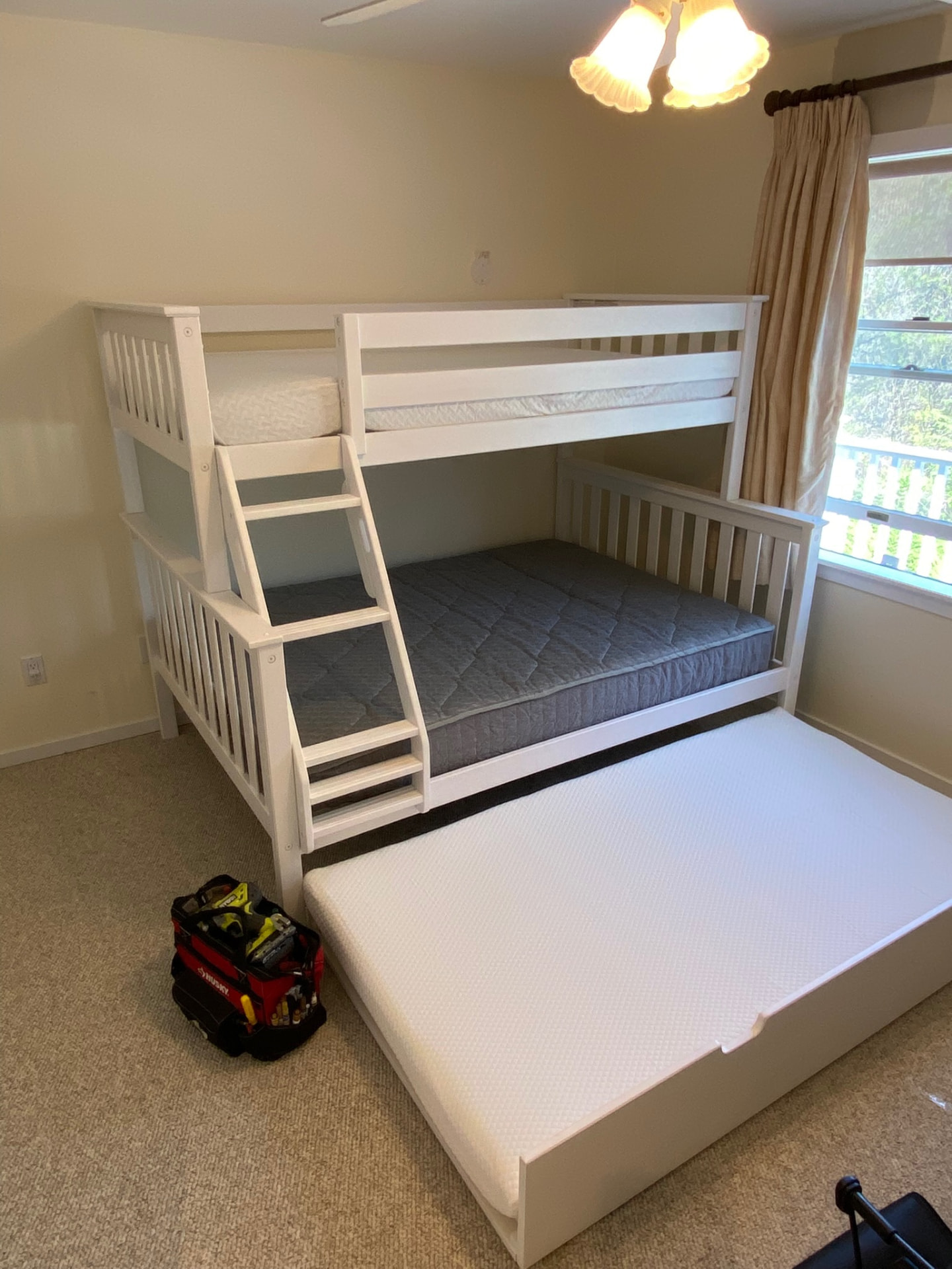 Assembled white bunk bed with ladder, mattresses and pull-out trundle