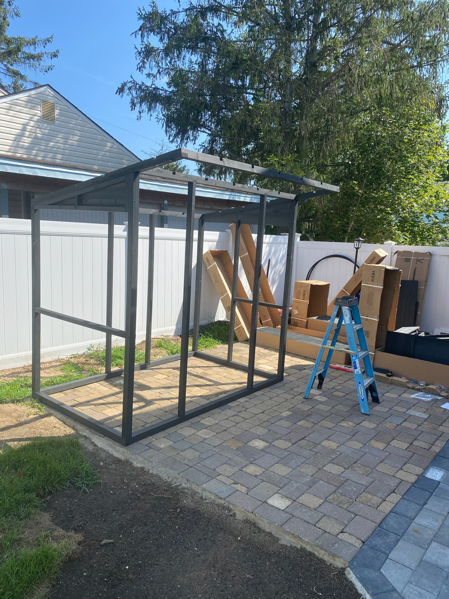 Metal frame of an outdoor shed being assembled on a backyard patio